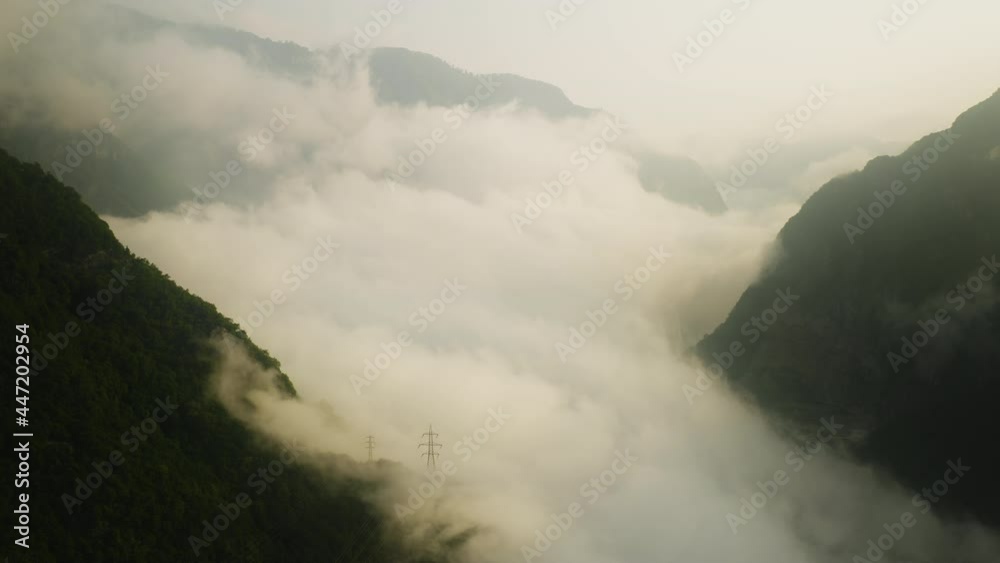 Mystic aerial flight through dense cloudscape between mountains ranges during sunrise. Drone flight in Italian alps. Mystic aerial flight through dense cloudscape between mountains ranges during sunrise. Drone flight in Italian alps.