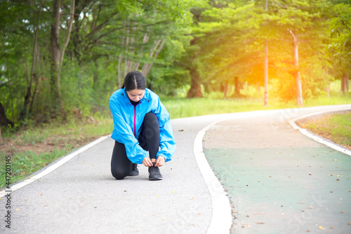 Young woman tying laces of running shoes before training. Female athlete tying laces for jogging on road . Sport lifestyle.Weight Loss and Healthy Concept