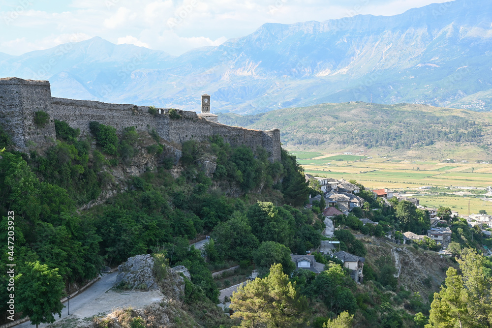 Panorama over Gjirokastra in Albania with the bell tower, clock tower of Kalaja e Gjirokastres castle with mountains in the background