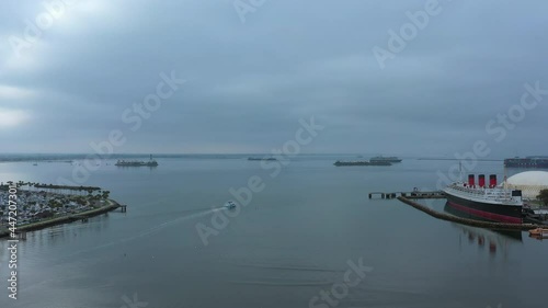 A motorboat leaving the Queensway Bay marina to the Pacific Ocean by the RMS Queen Marry - aerial view  photo