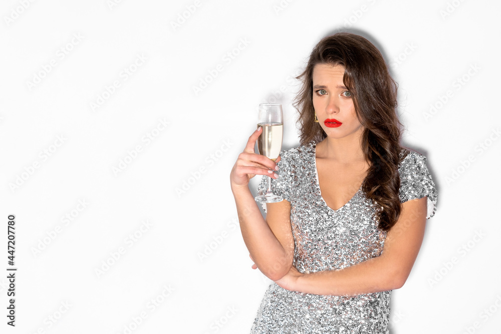 Corporate party. Sad woman. Boring celebration. Bad holiday. Unhappy lady spangle silver dress holding champagne glass isolated white copy space. Corporate party. Sad woman. Boring celebration. Bad holiday. Unhappy lady spangle silver dress holding champagne glass isolated white copy space.