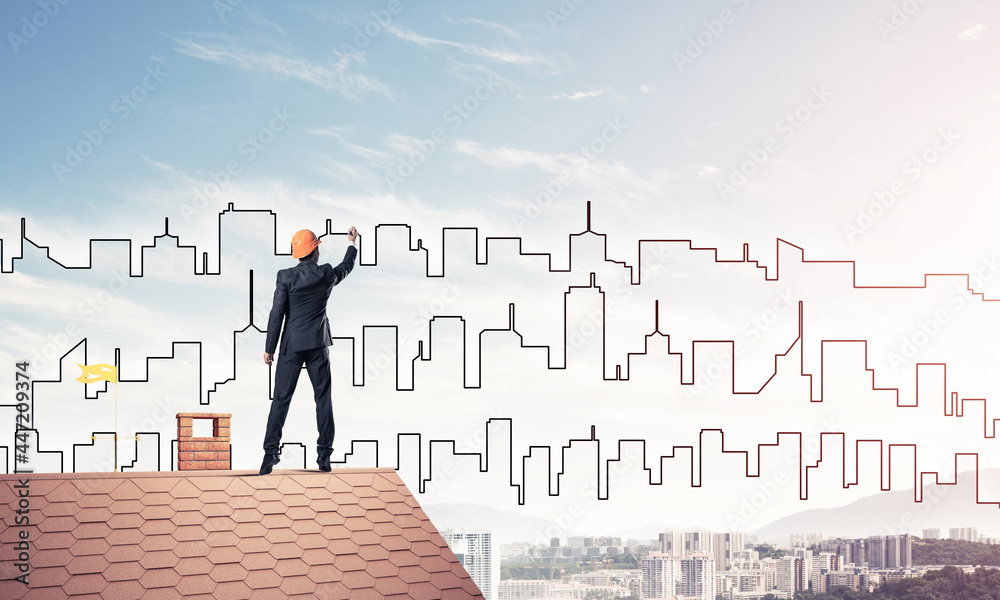 Man architect draw silhouette of modern city on blue sky. Mixed