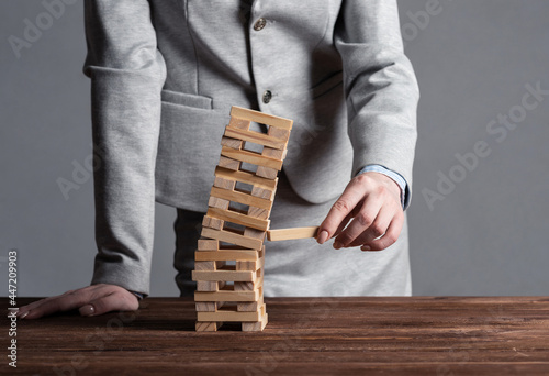 Fotografie, Tablou Businesswoman removing wooden block from tower