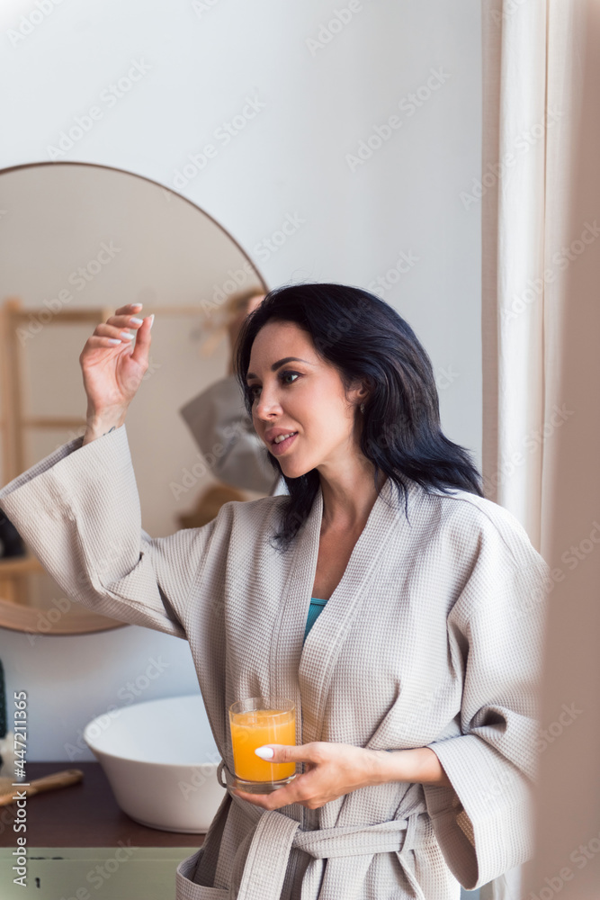young beautiful woman in bathrobe holding orange juice glass, self care concept young beautiful woman in bathrobe holding orange juice glass, self care concept