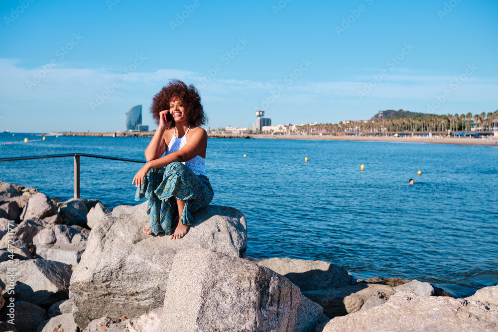 a curvy black afro woman using smartphone at Barcelona beach