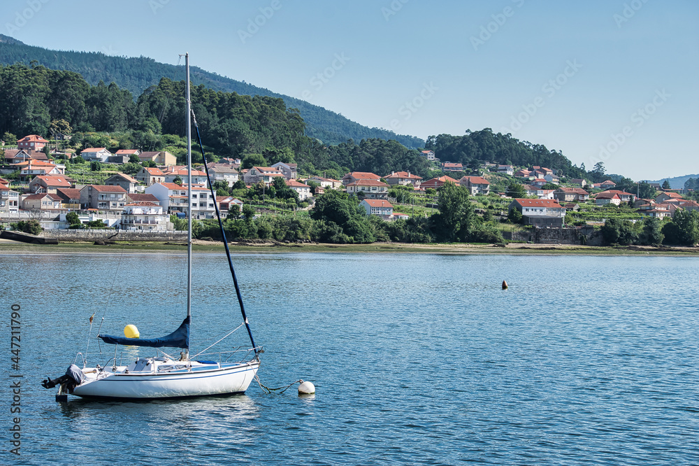 Obraz premium Barco velero fondeado en el estuario de la ría de Pontevedra junto a la villa de Combarro, España