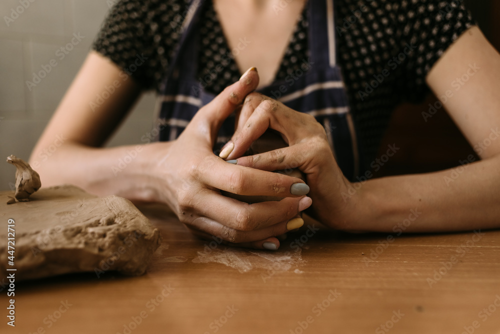 Obraz premium close-up Hands of a woman sculptor knead clay on the table at home. Hobby clay modeling.