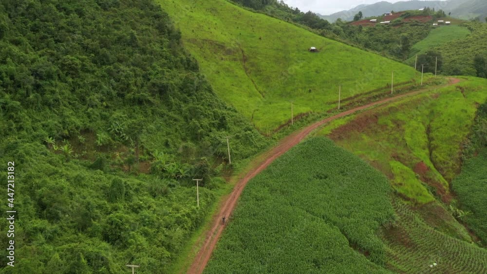 Aerial view of countryside road passing through the lush greenery and foliage tropical rain forest mountain landscape in the Northern Thailand, Nan province. Aerial view of countryside road passing through the lush greenery and foliage tropical rain forest mountain landscape in the Northern Thailand, Nan province.