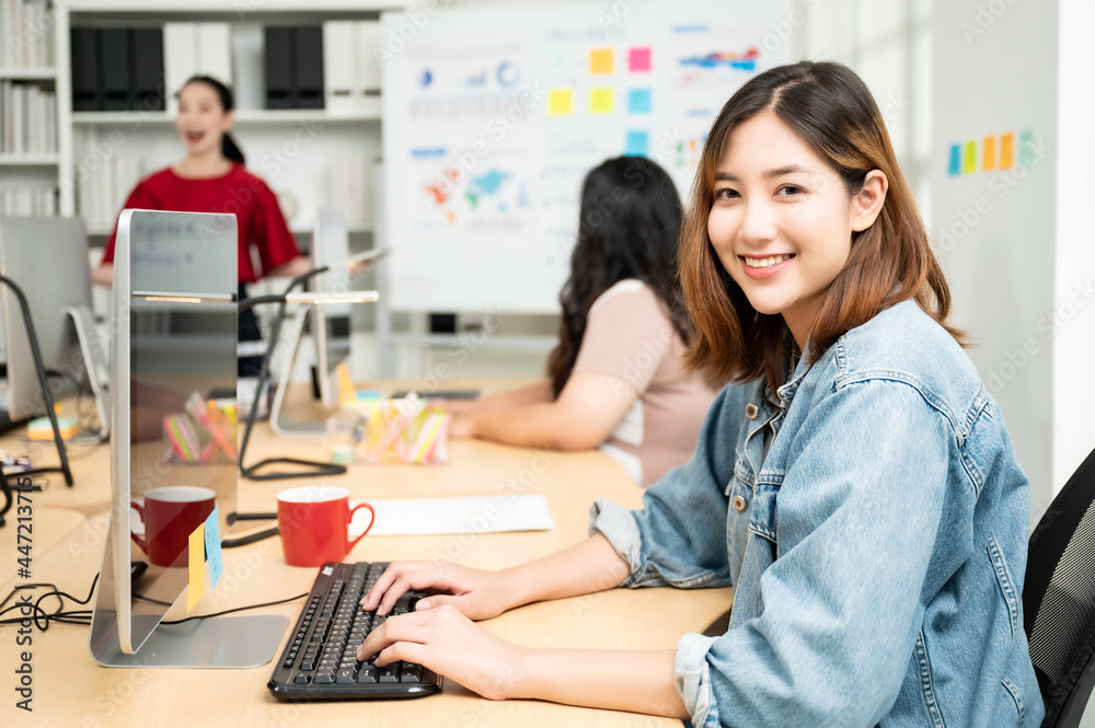 Beautiful asian woman working on computer at workplace. She looked straight at the camera and showed confidence. Beautiful asian woman working on computer at workplace. She looked straight at the camera and showed confidence.