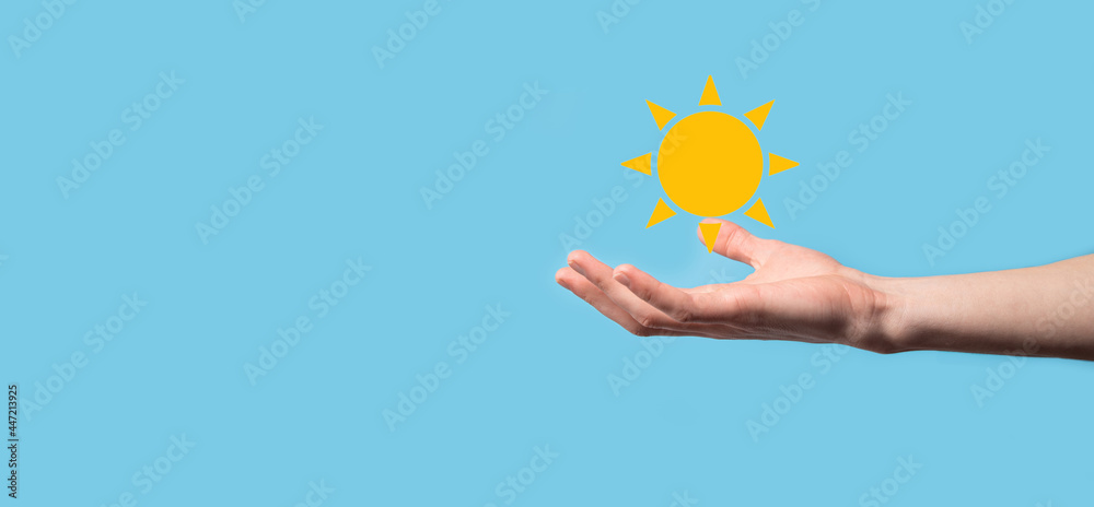 Hand on blue background holds sun icon symbol.Sustainable source of electricity, power supply concept. Eco environmentally friendly technology approach. Hand on blue background holds sun icon symbol.Sustainable source of electricity, power supply concept. Eco environmentally friendly technology approach.
