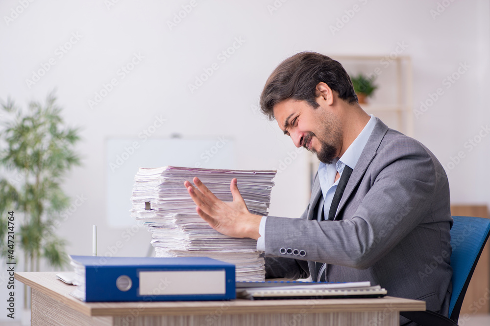 Young male employee and too much work in the office Young male employee and too much work in the office