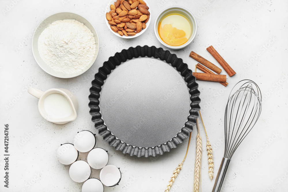 Baking form with ingredients for preparing cake and utensils on light background Baking form with ingredients for preparing cake and utensils on light background