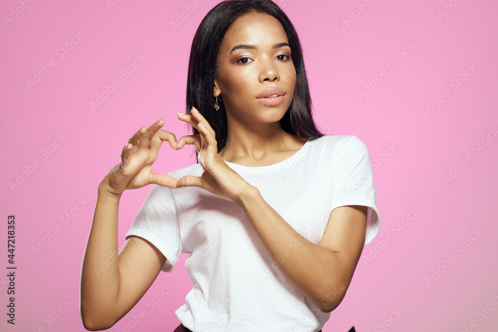 Woman in white t-shirt hairstyle cosmetics studio posing pink background Woman in white t-shirt hairstyle cosmetics studio posing pink background