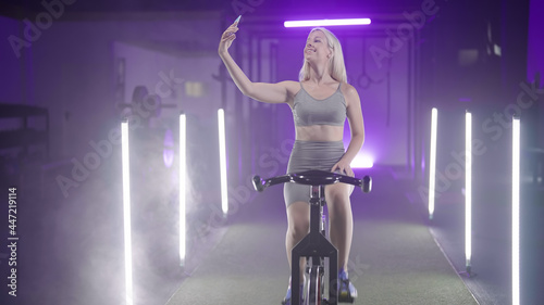 Instagramer fitness girl making a selfie photo on gym bicycle in neon lights © Video_StockOrg