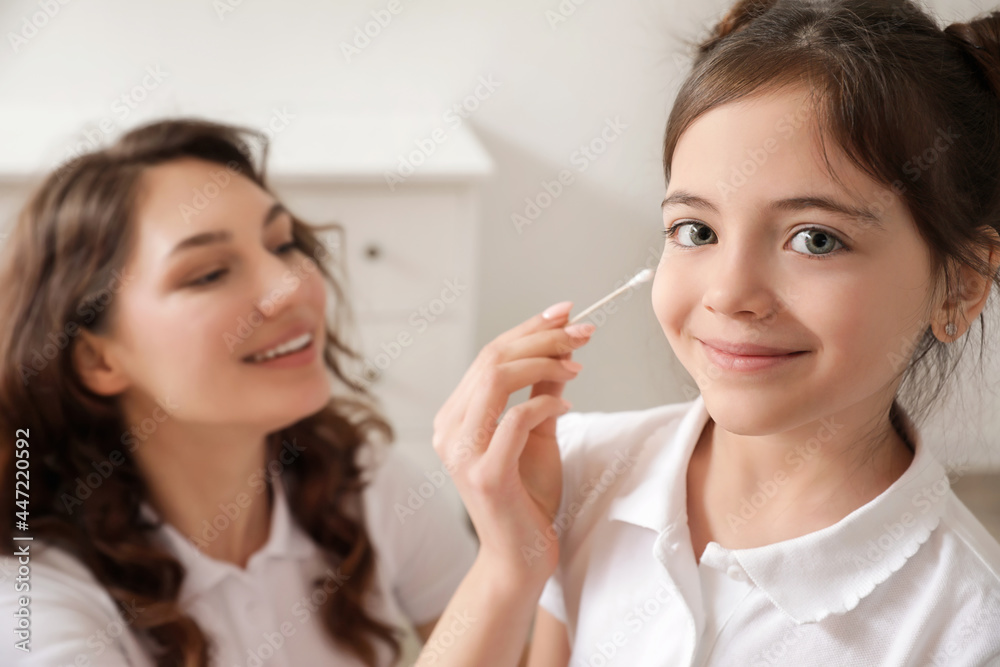 Mother cleaning her daughter's ears at home Mother cleaning her daughter's ears at home