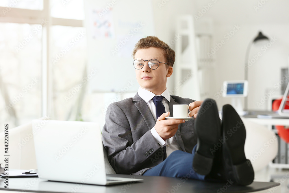 Young man drinking coffee in office Young man drinking coffee in office