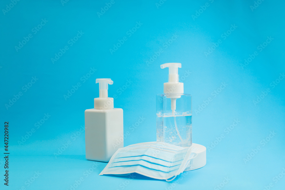 Two bottles of hand sanitisers in a blue backdrop and surgical masks to fight against the pandemic. Protect yourself from the covid 19 viruses. Two bottles of hand sanitisers in a blue backdrop and surgical masks to fight against the pandemic. Protect yourself from the covid 19 viruses.