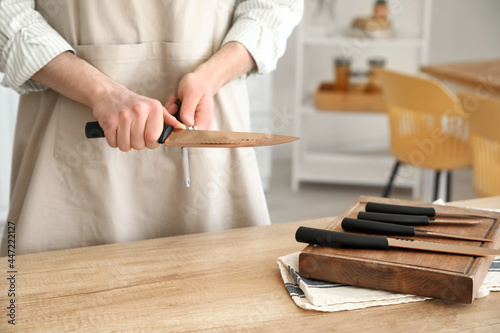 Woman sharpening knife in kitchen
