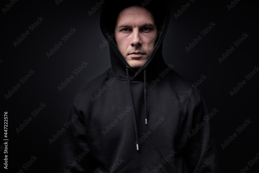 Male in black outfit is looking at camera, maniac or killer, isolated on black studio. Portrait of caucasian guy commit crime, kidnapping people. Crime, violence. threat to life, stop violence
