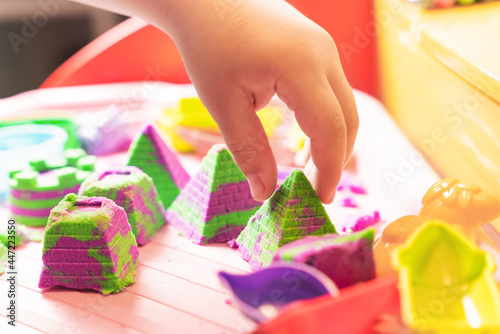 Hands of a child playing with multicolored kinetic sand