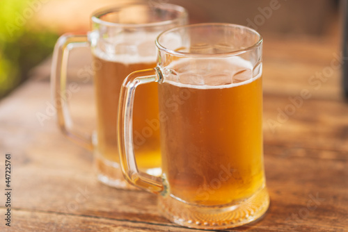 Two beer mugs closeup on wooden natural table.Two glass beer on wood background.