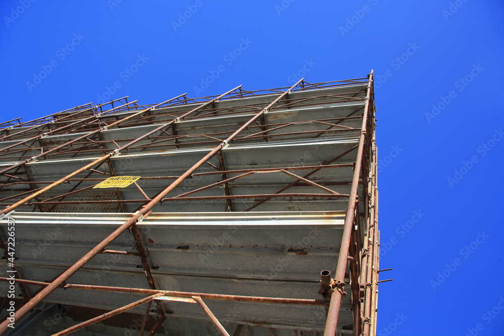 Steel beam structure, building under construction with blue sky. Side perspective view
