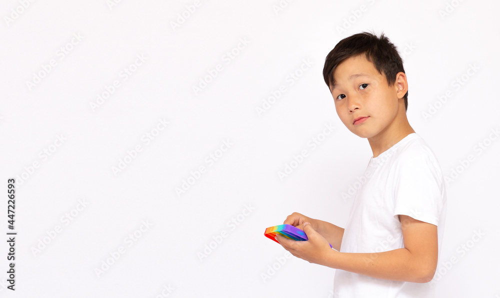 Blonde boy playing with rainbow pop it fidget toy. Push bubble fidget sensory toy - washable and reusable stress relief toy. Antistress toy for child with special needs. Mental health concept Blonde boy playing with rainbow pop it fidget toy. Push bubble fidget sensory toy - washable and reusable stress relief toy. Antistress toy for child with special needs. Mental health concept