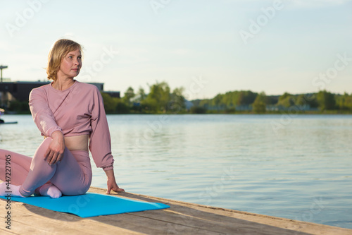 Sport Ideas. Senior Caucasian Woman in Sport Outfit Practicing Stretching Yoga On Wooden Stage Near Water Outdoor