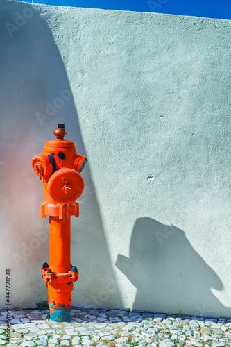 Closeup View of Old Styled Red Fire Cock Hydrant Against of Wall Located On One of The Streets in Portugal. photo