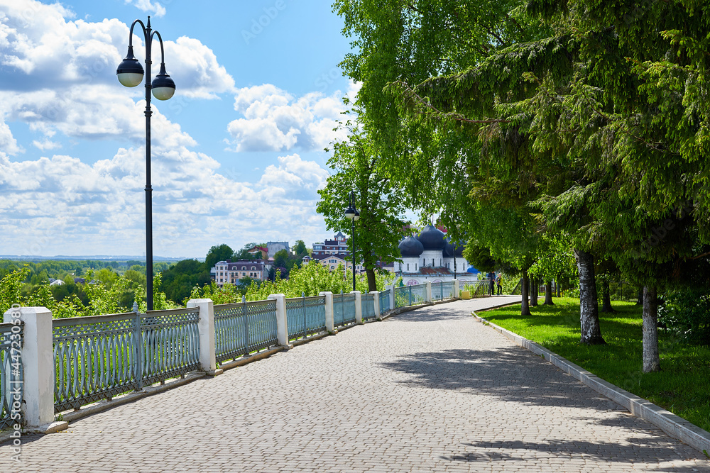 Kirov, Russia - May 28, 2020: An alley with a fence with white columns in a city park on a sunny summer day