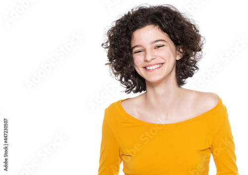 Studio portrait of a young smiling confident girl with curly hair on white background. Waist up studio portrait of a smiling teen girl.