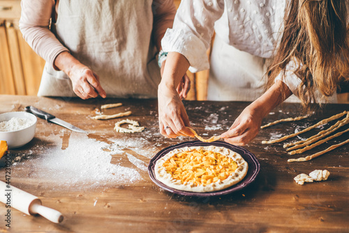 Mother and adult daughter baking pumpkin pie together at home.