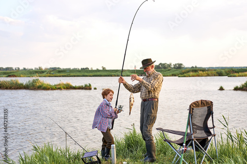 Man family fishing. cheerful Boy with grandfather catch the fish, fly fishing outdoor over river background. Old and young. Family time, hobby, happy childhood concept. copy space