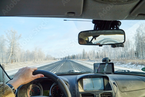 Siberia, Russia - November 28, 2020: View from of car interior from side of driver to the road and nature landscape through the windshield
