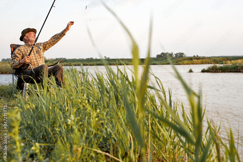 Senior man fishing. Fishing on the lake. Fish on hook. Master baiter. Gone fishing. Summer vacation. gray-bearded man catching fish. Retirement fishery, alone outdoors in nature Senior man fishing. Fishing on the lake. Fish on hook. Master baiter. Gone fishing. Summer vacation. gray-bearded man catching fish. Retirement fishery, alone outdoors in nature