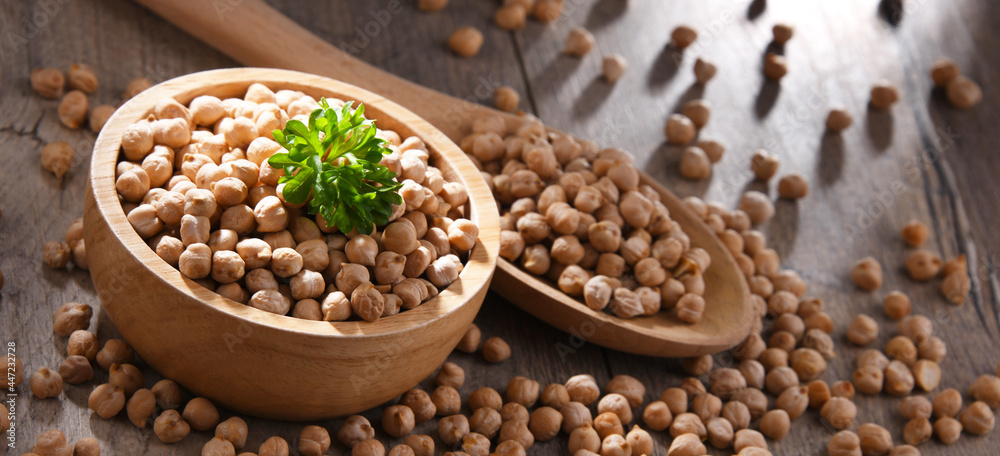 Bowl and spoon of chickpeas on wooden table Bowl and spoon of chickpeas on wooden table
