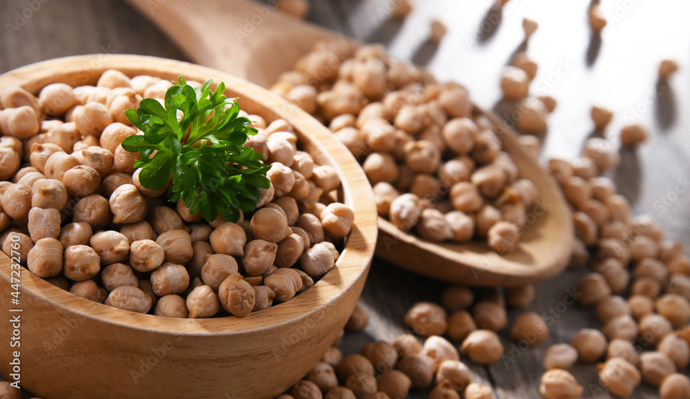 Bowl and spoon of chickpeas on wooden table Bowl and spoon of chickpeas on wooden table