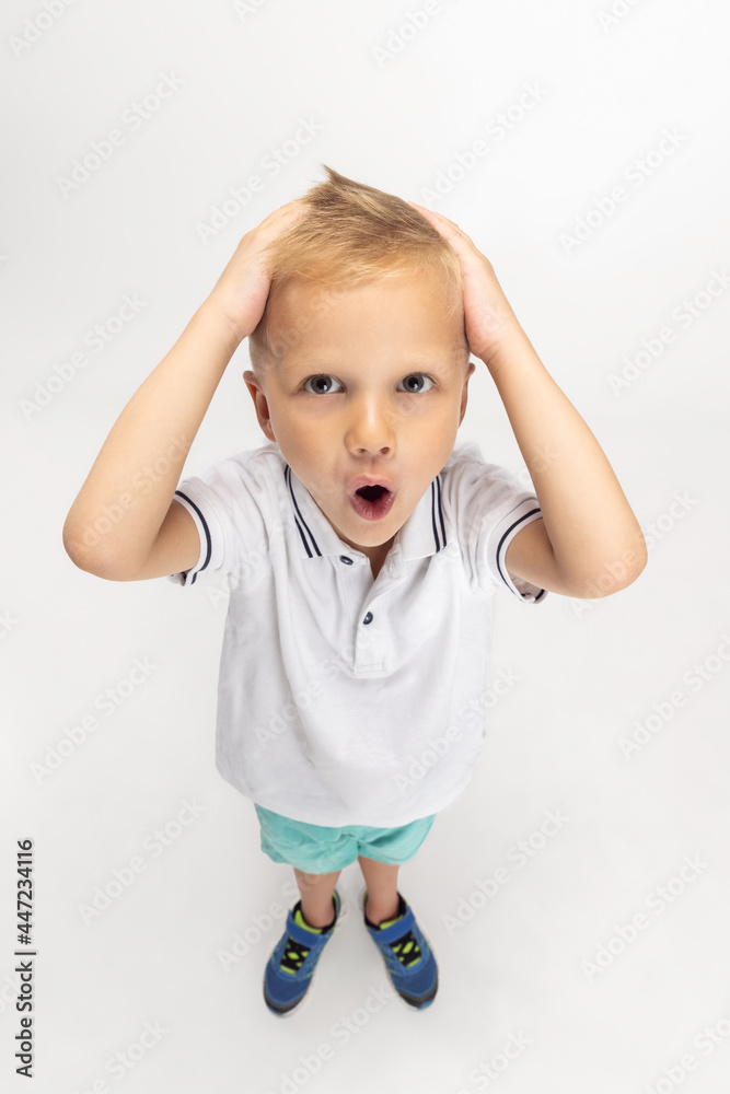 High angle view of Caucasian preschool boy isolated on white studio background. Copyspace for ad. Childhood, education, emotion concept High angle view of Caucasian preschool boy isolated on white studio background. Copyspace for ad. Childhood, education, emotion concept