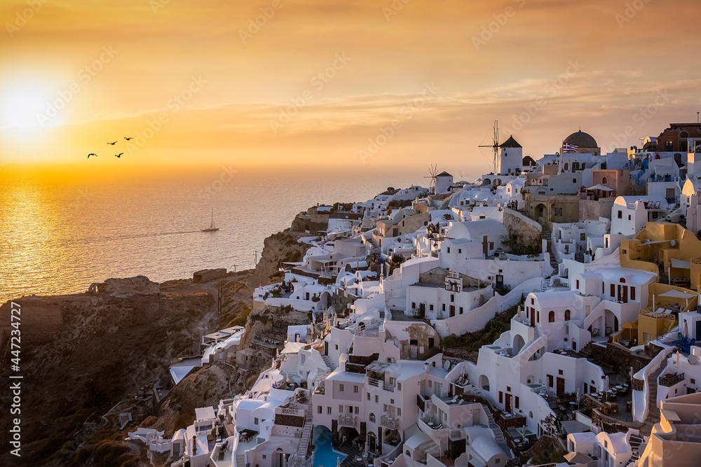 Orange summer sunset behind the beautiful village of Oia, situated at the edge of the cadera at Santorini island, Cyclades, Greece