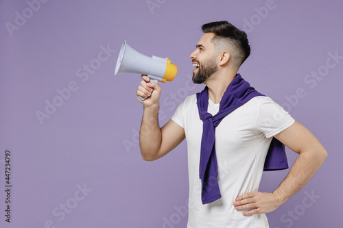 Side view profile fascinating fun young brunet man 20s wears white t-shirt purple shirt hold scream in megaphone announces discounts sale Hurry up isolated on pastel violet background studio portrait