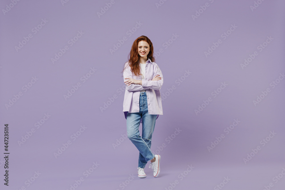 Full size body length stunning fun young redhead curly green-eyed woman 20s wears white T-shirt violet jacket hold hands legs crossed isolated on pastel purple color wall background studio portrait. Full size body length stunning fun young redhead curly green-eyed woman 20s wears white T-shirt violet jacket hold hands legs crossed isolated on pastel purple color wall background studio portrait.
