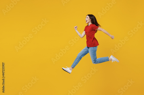 Full size body length side view profile vivid young brunette woman 20s wear basic red t-shirt jumping running Hurry up isolated on yellow background studio portrait. People emotions lifestyle concept