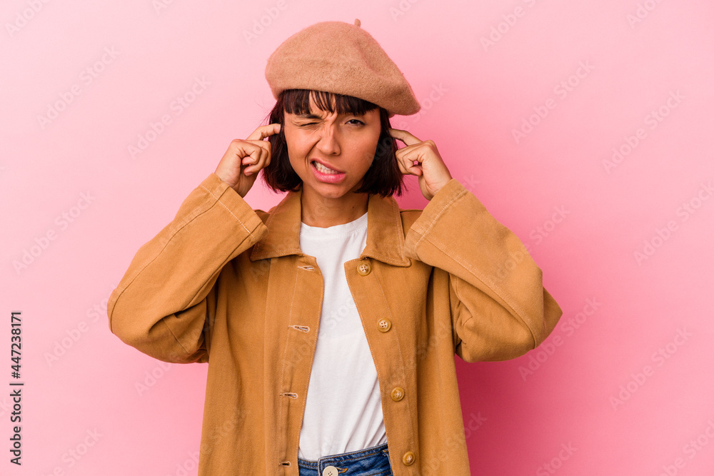 Young mixed race woman isolated on pink background covering ears with fingers, stressed and desperate by a loudly ambient. Young mixed race woman isolated on pink background covering ears with fingers, stressed and desperate by a loudly ambient.