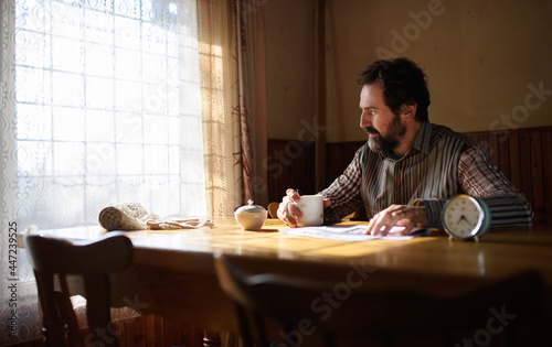 Portrait of unhappy poor mature man reading newspapers indoors at home  poverty concept.