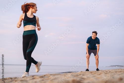 Full length couple young two friend strong sporty sportswoman sportsman woman man in sport clothes warm up training running on sand sea ocean beach outdoor jog on seaside in summer day cloudy morning.