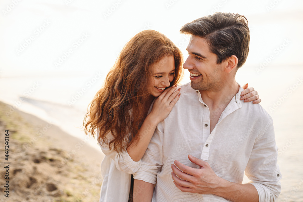 Happy fun young couple two friends family man woman in casual clothes hug girlfriend put head on boyfriend shoulder at sunrise over sea beach ocean outdoor exotic seaside in summer day sunset evening. Happy fun young couple two friends family man woman in casual clothes hug girlfriend put head on boyfriend shoulder at sunrise over sea beach ocean outdoor exotic seaside in summer day sunset evening.