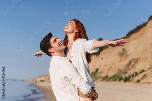 Side view relaxed young couple two friends family man woman in white clothes boyfriend hold girlfriend with outsretched arm at sunrise over sea sand beach outdoor seaside in summer day sunset evening