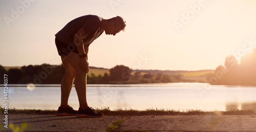 Photos A young man jogging at sunset by the lake.