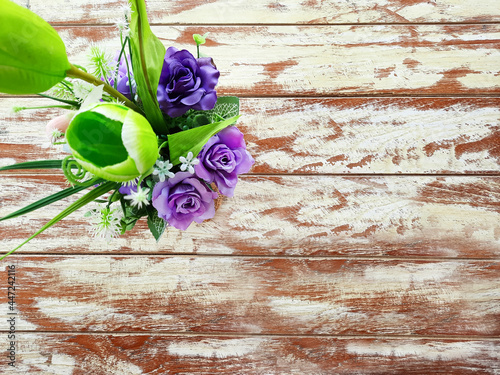 Purple flowers in a vase set on a beautifully patterned wooden table.