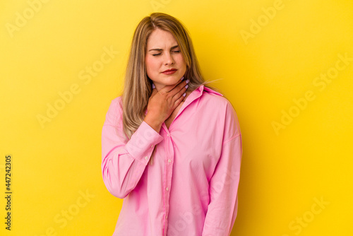 Young russian woman isolated on yellow background suffers pain in throat due a virus or infection. © Asier